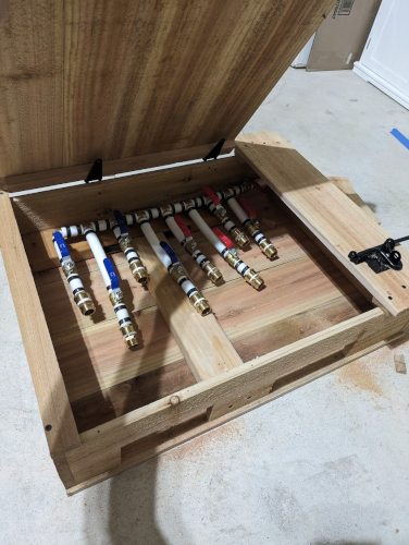 Box with a hinged lid and latch mounted to the outside - opened so you can see the pipe fittings