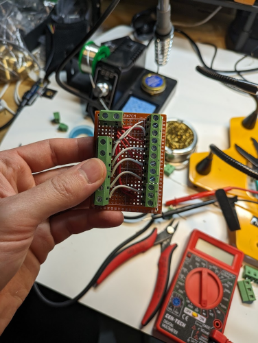 Rectangular PCB with soldered terminals and wires connecting the sides