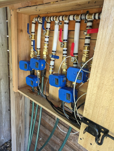 Open sprinkler valve box with blue mechanical valves installed at the base of each pipe line (zone)