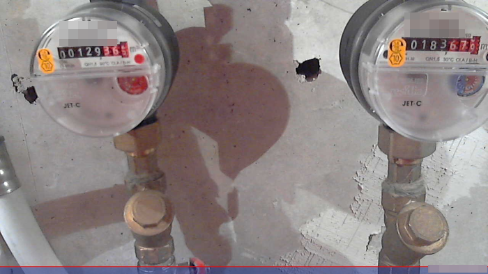Shot of two well-lit water meters against a concrete ceiling